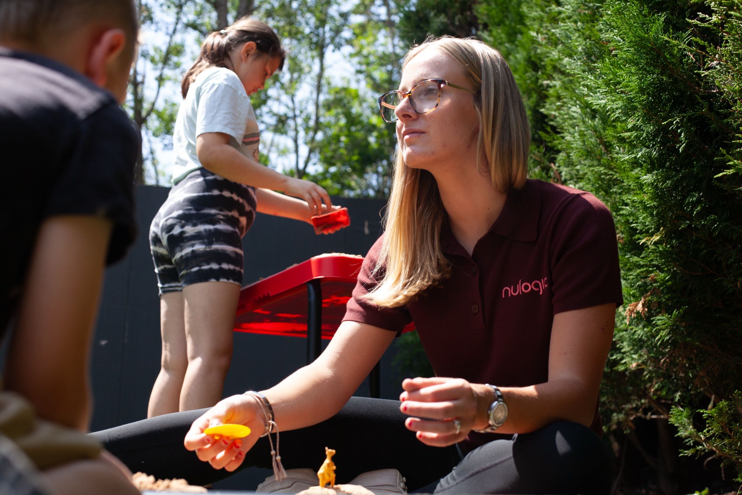 A Nulogic practitioner plays outdoors with young children on a sunny day.